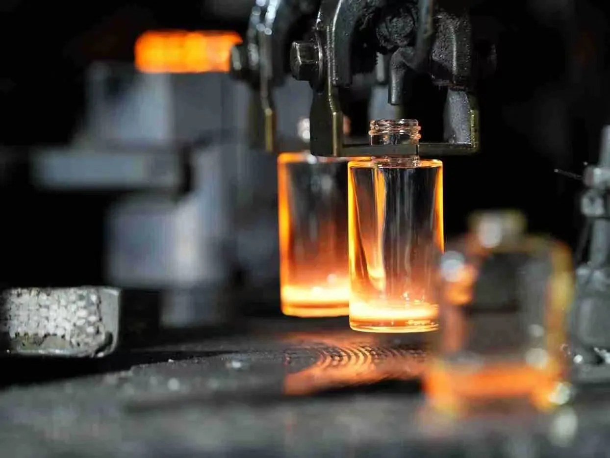 Close-up of hot glass bottle forming on production machine