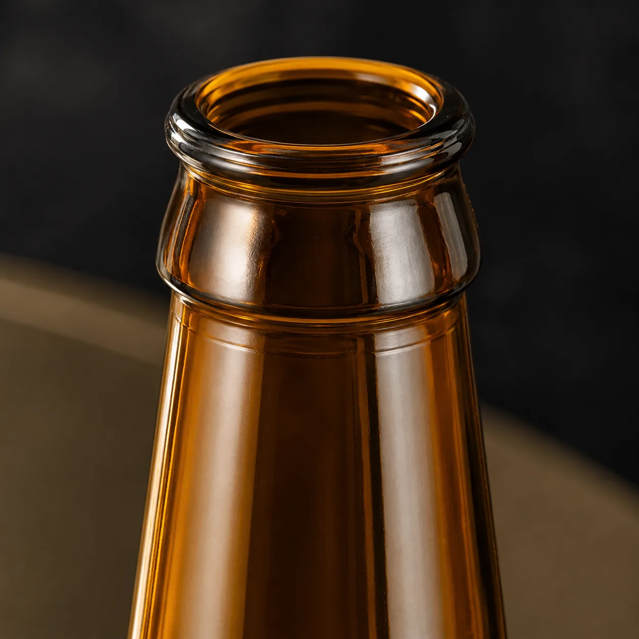Close view of Amber Glass Embossed Beverage Bottle showing closure area and embossed detail / decoration