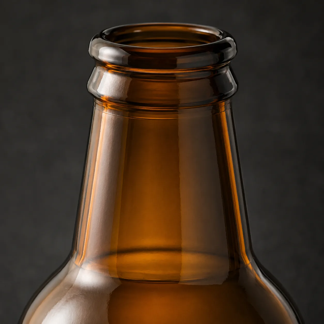 Close view of Amber Glass Stubby Beer Bottle showing closure area and print / coat / label